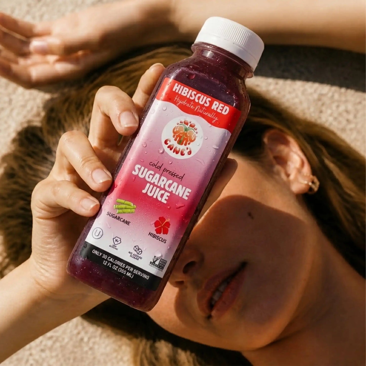 Person holding a bottle of hibiscus red sugarcane juice.